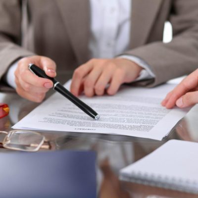 Group of business people and lawyers discussing contract papers sitting at the table, close up